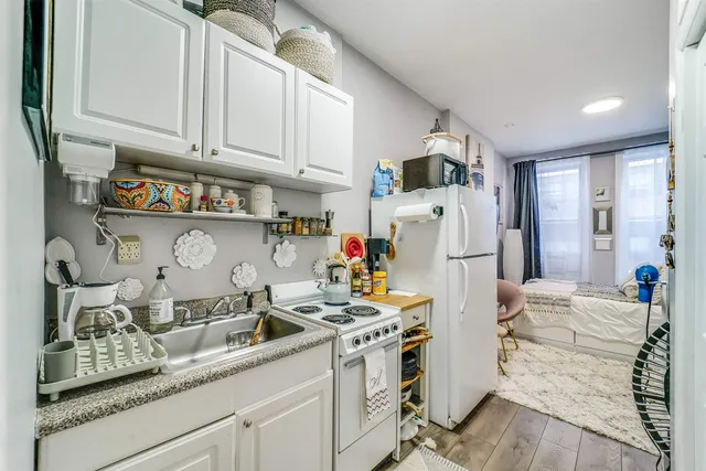 a kitchen with a sink dishwasher a refrigerator and cabinets with wooden floor