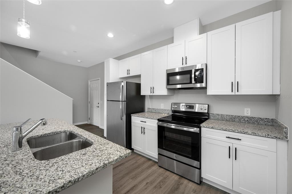 2115 Sebring Place Clearwater, FL 33760 - Photo 9 of 59 a kitchen with granite countertop white cabinets and stainless steel appliances