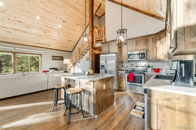 a kitchen with stainless steel appliances granite countertop a sink a stove and a wooden floors