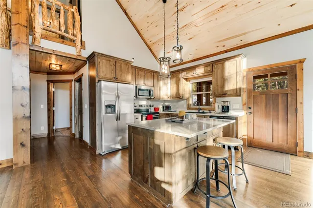 a kitchen with stainless steel appliances granite countertop a refrigerator a stove a sink dishwasher and a dining table with wooden floor