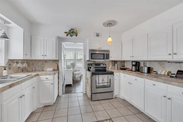 a kitchen with white cabinets appliances and sink