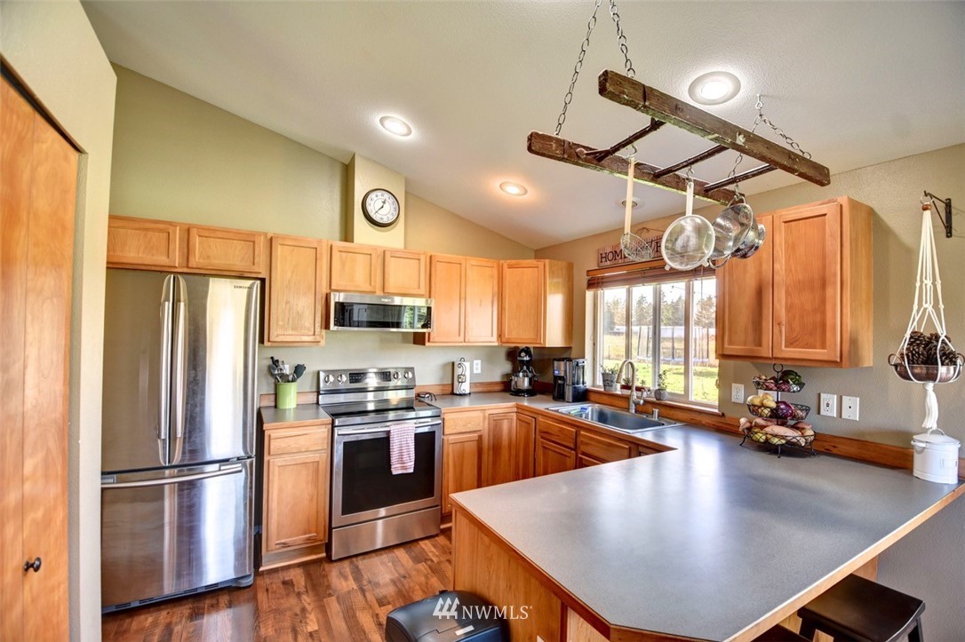 5124 183rd Lane Southwest Rochester, WA 98579 - Photo 6 of 31 a kitchen with stainless steel appliances wooden floor a refrigerator a sink a stove and white cabinets