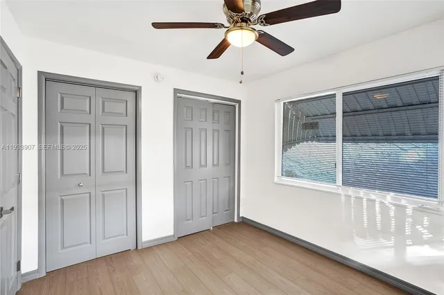 an empty room with wooden floor fan and windows