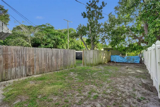 a view of a backyard with large trees and wooden fence