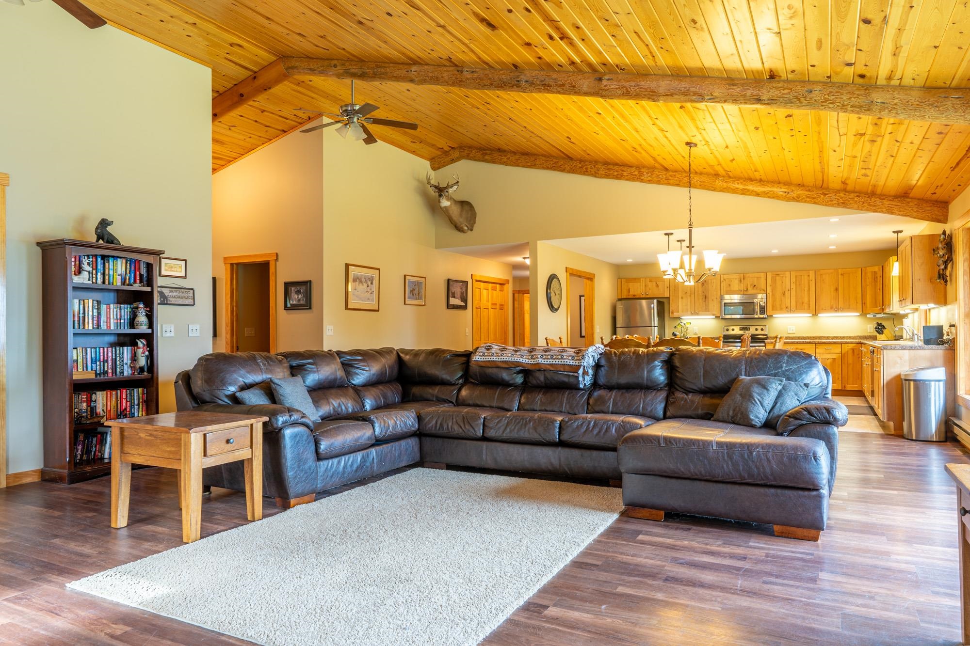 1663 Saari Road Ely, MN 55731 - Photo 7 of 31 Living room featuring a wood ceiling with exposed beams, high vaulted ceiling, ceiling fan, dark wood-type flooring, and a chandelier