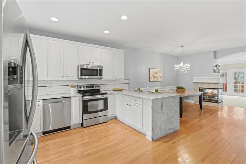 1200 Wing Street, Unit 8 Atlanta, GA 30350 - Photo 13 of 54 a kitchen with stainless steel appliances granite countertop a stove top oven a sink dishwasher a refrigerator and a dining table with wooden floor