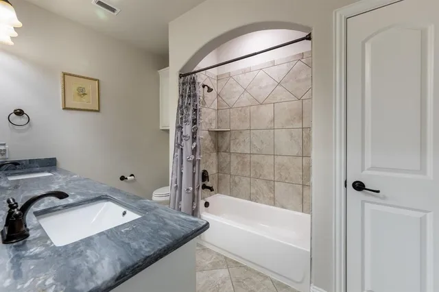 a bathroom with a granite countertop sink and a bathtub