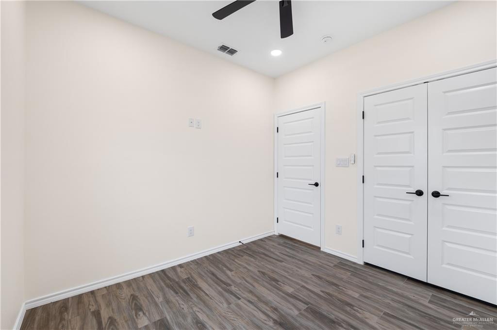 18054 Spruce Street Combes, TX 78552 - Photo 14 of 25 Interior room featuring wood-finish flooring, white paneled doors with black hardware, and a ceiling fan with integrated lighting