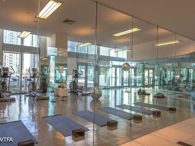 92 Southwest 3rd Street, Unit 3808 Miami, FL 33130 - Photo 7 of 15 a gym hall with lots of white furniture and floor to ceiling window