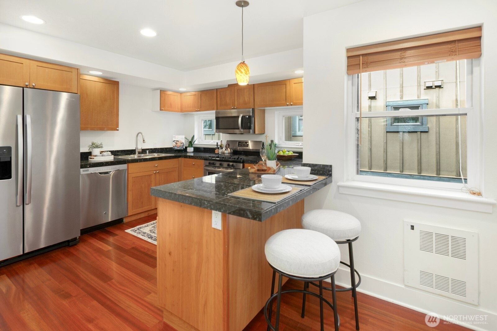 921 North 35th Street, Unit B Seattle, WA 98103 - Photo 10 of 28 a kitchen with stainless steel appliances granite countertop a stove a refrigerator a sink a dining table and chairs with wooden floor