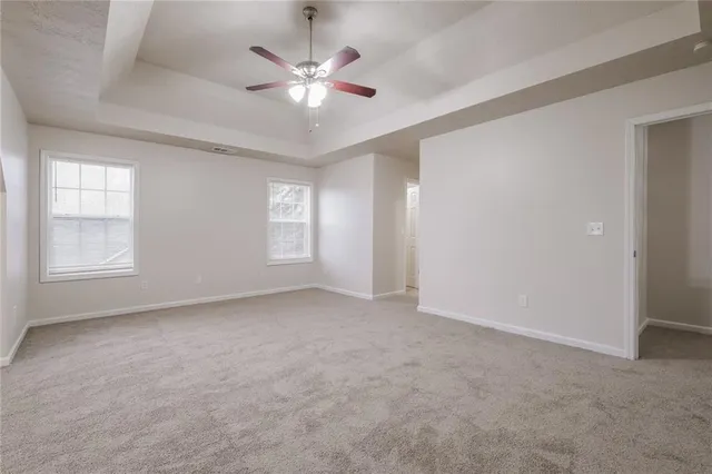 an empty room with chandelier fan and windows