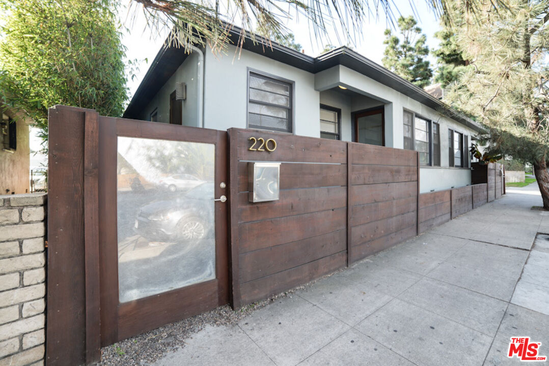 a view of a wooden house with a large window and wooden fence