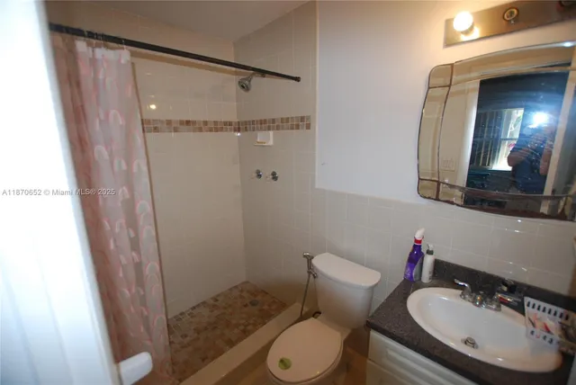 a bathroom with a sink a toilet a mirror and shower