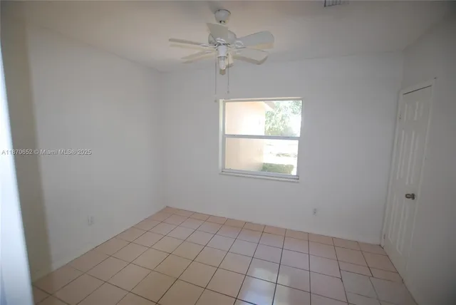 an empty room that has a window and a fan