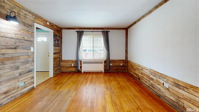 a view of an empty room with a window and wooden floor