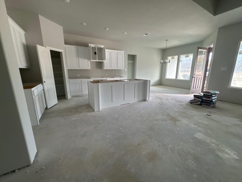 152 Oak Grv Way Springtown, TX 76082 - Photo 6 of 10 Kitchen with white cabinets, a center island, concrete flooring, and a chandelier