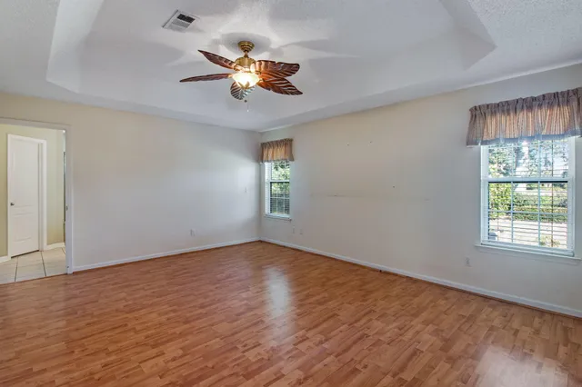 a view of an empty room with a window and wooden floor