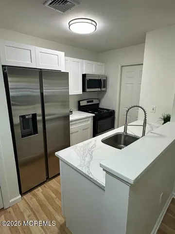 a kitchen with stainless steel appliances granite countertop a refrigerator a stove a sink and a microwave