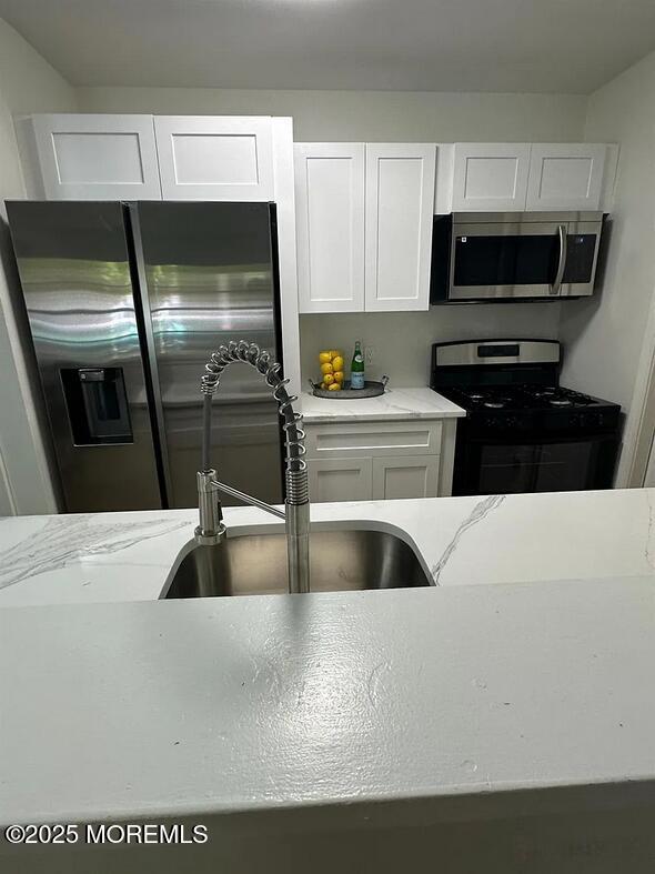 28 Delavan Court New Brunswick, NJ 08901 - Photo 5 of 10 a kitchen with a refrigerator a stove a microwave and cabinets