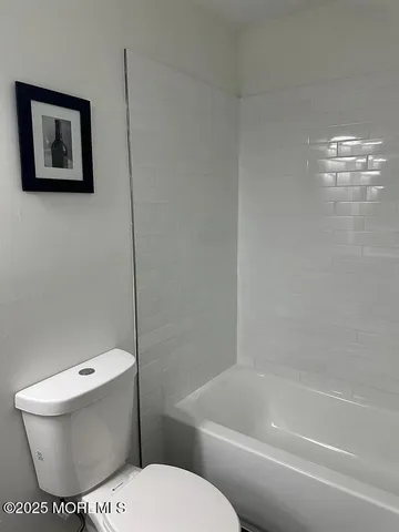 a white toilet sitting next to a bath tub