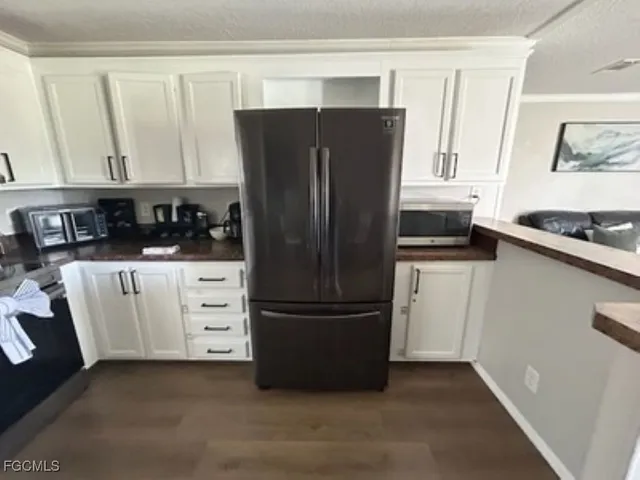 a kitchen with white cabinets and refrigerator