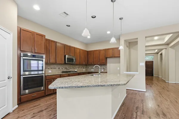 a kitchen with kitchen island granite countertop a stove a sink and a refrigerator with wooden floor