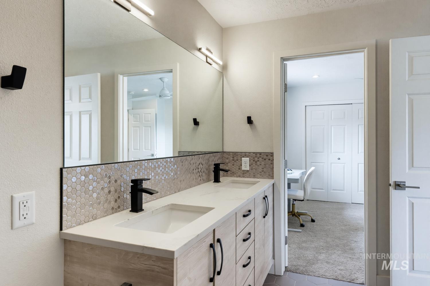 369 South Winthrop Way Boise, ID 83709 - Photo 35 of 50 Dual vanity featuring matte black hardware, integrated sinks, a light-toned countertop, and a mosaic tile backsplash