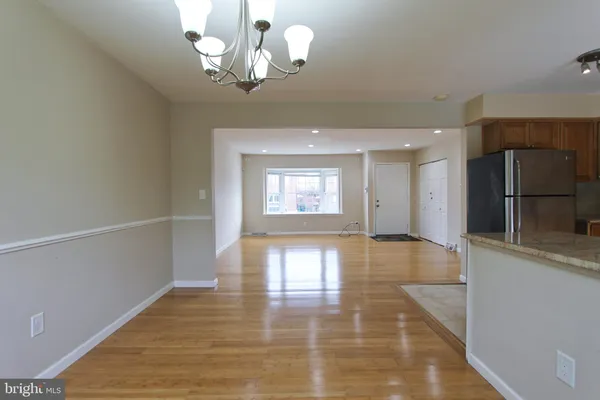 a view of a hallway with wooden floor and a kitchen