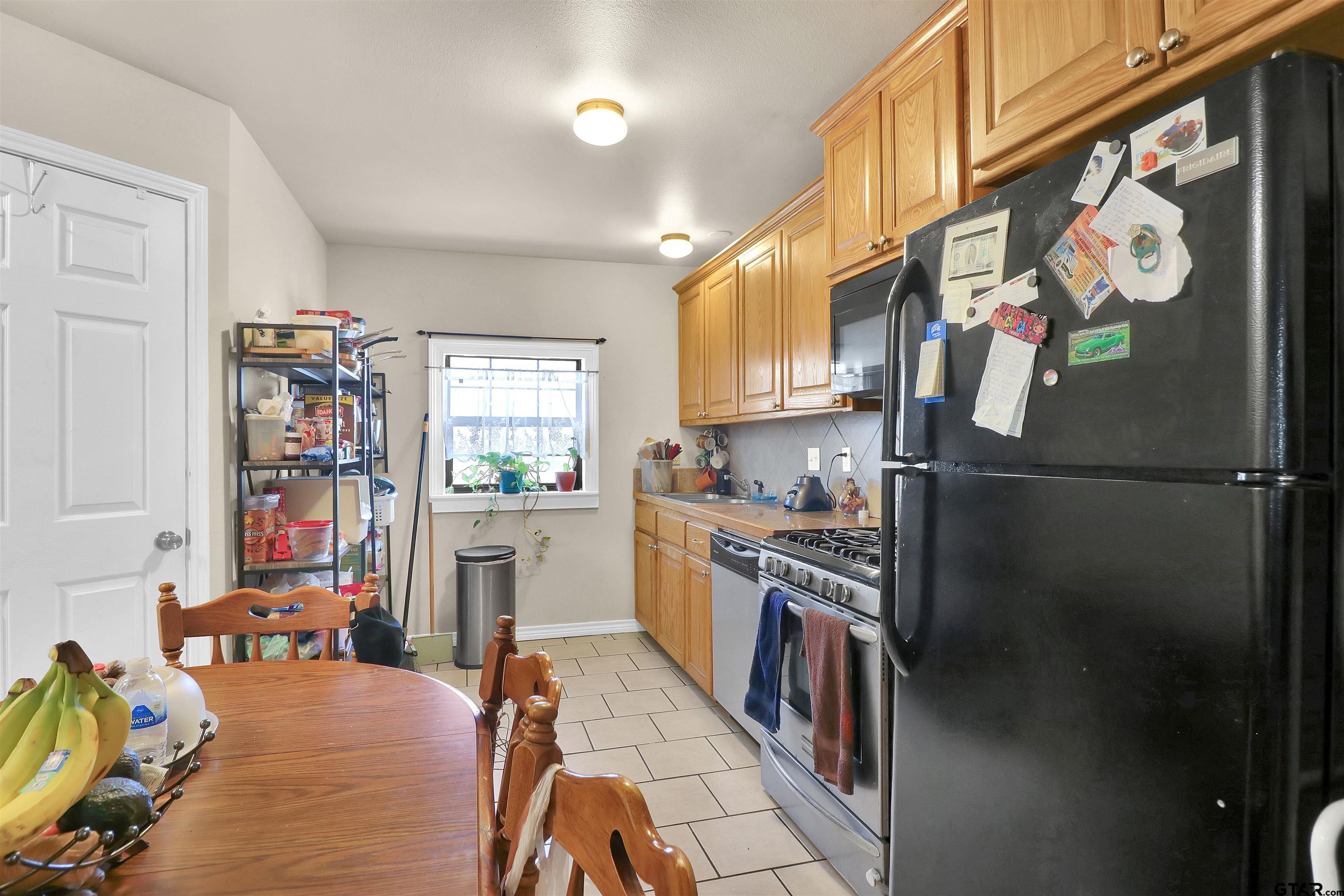 1224 West 3rd Street Tyler, TX 75701 - Photo 4 of 14 a kitchen with stainless steel appliances granite countertop a refrigerator a stove and a sink