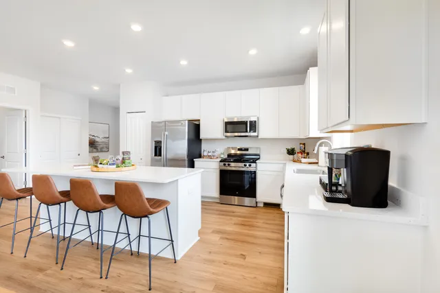 a kitchen with a sink a microwave a stove and white cabinets