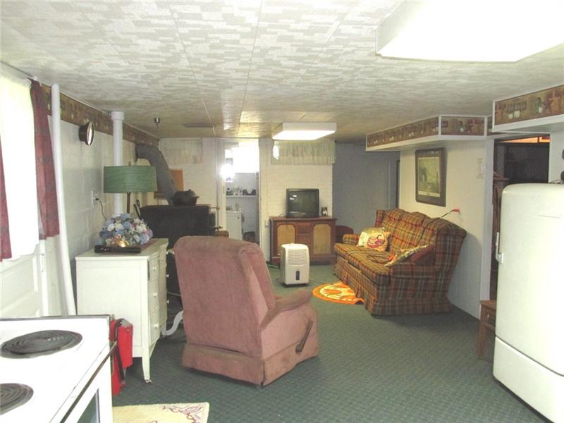 380 Dillon Road Acme, PA 15610 - Photo 18 of 25 On the left is a wood burner that can heat the entire home! The second full bath has the open door at the back left of the picture. To the right beside the fridge is the entry to the other side of the basement.