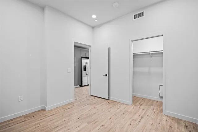 a view of an empty room with wooden floor and closet