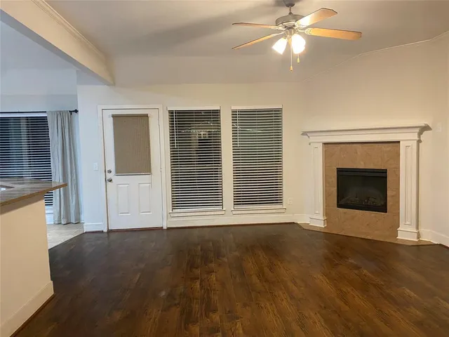 a view of an empty room with wooden floor and a fireplace