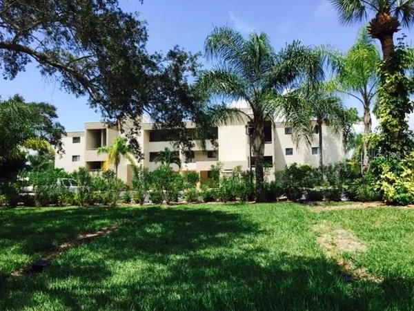 a front view of a house with a yard and palm trees