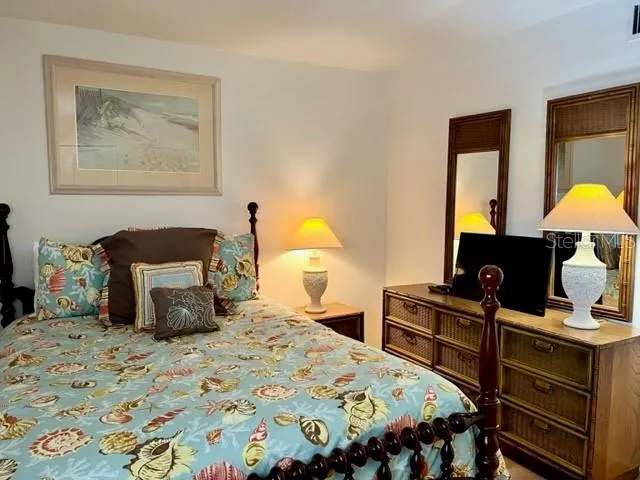 a bedroom with a bed and a lamp on dresser