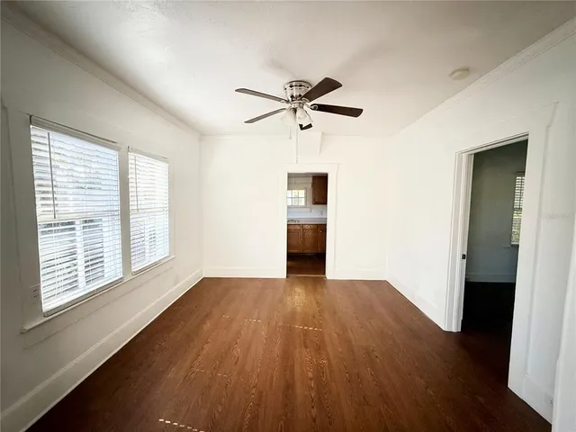 a view of empty room with wooden floor and fan