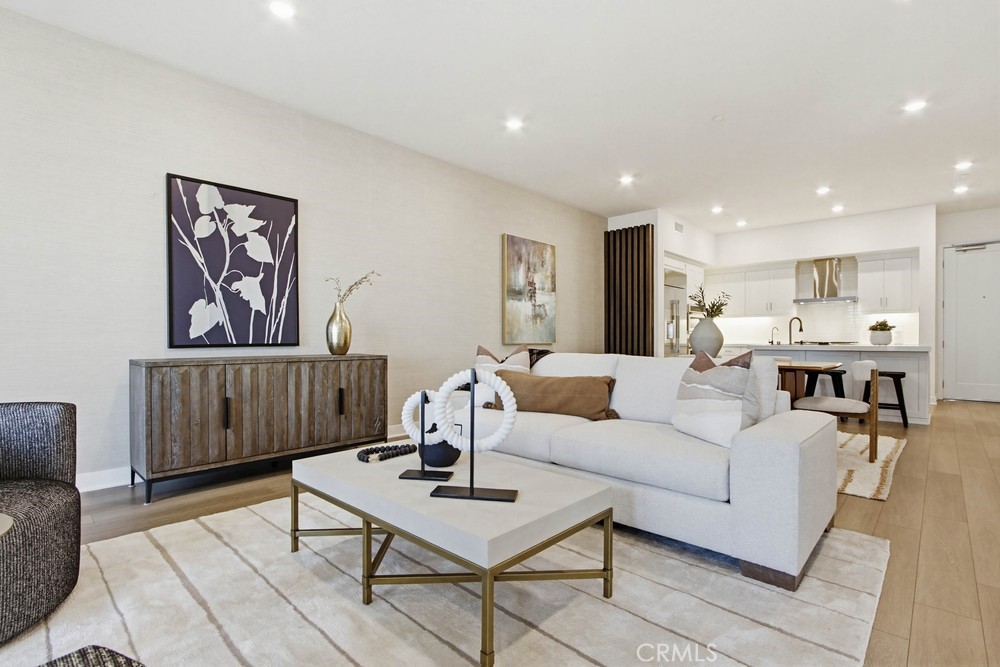 a living room with furniture a table and kitchen view