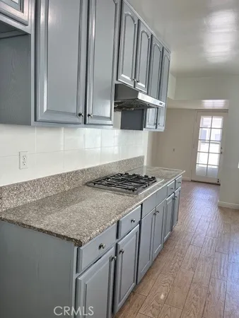 a kitchen with stainless steel appliances granite countertop a sink dishwasher a refrigerator and wooden floor