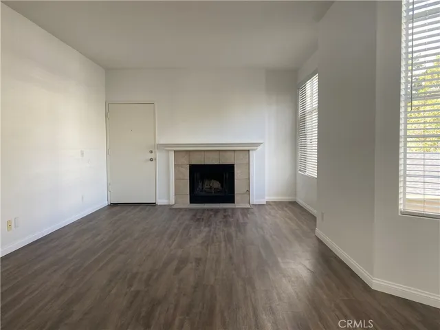 an empty room with wooden floor fireplace and windows
