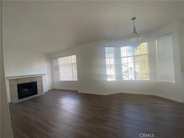 an empty room with wooden floor fireplace and windows