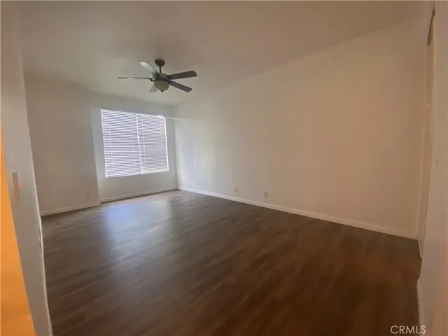 an empty room with wooden floor fan and windows
