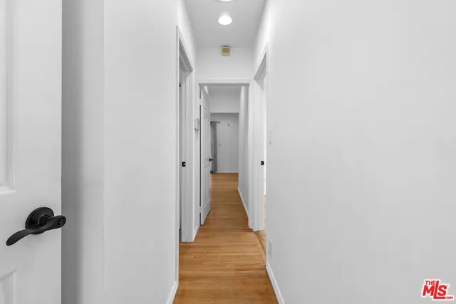 a view of a hallway with wooden floor and a bathroom