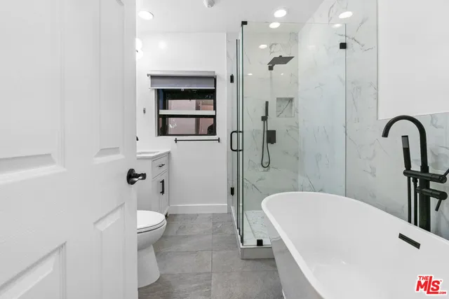 a bathroom with a tub a toilet and a shower