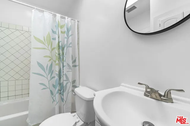 a bathroom with a sink and mirror with toilet