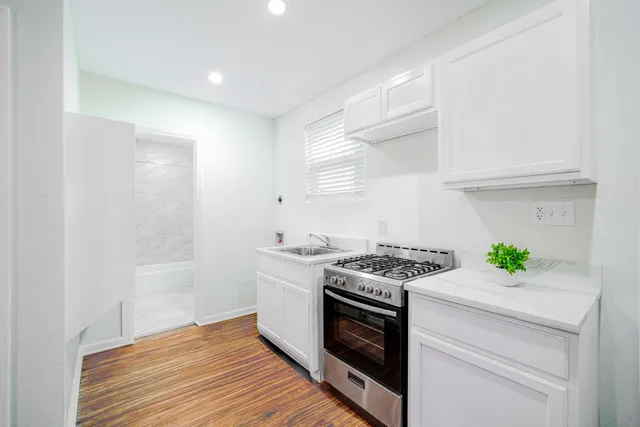 a kitchen with granite countertop a stove and a wooden floor