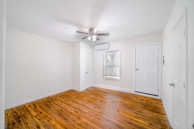 a view of a room with wooden floor and a ceiling fan