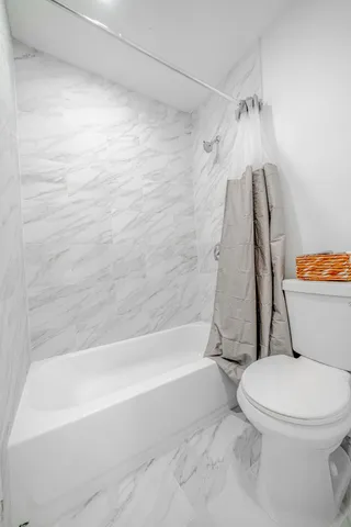 a white toilet sitting next to a bath tub and a shower