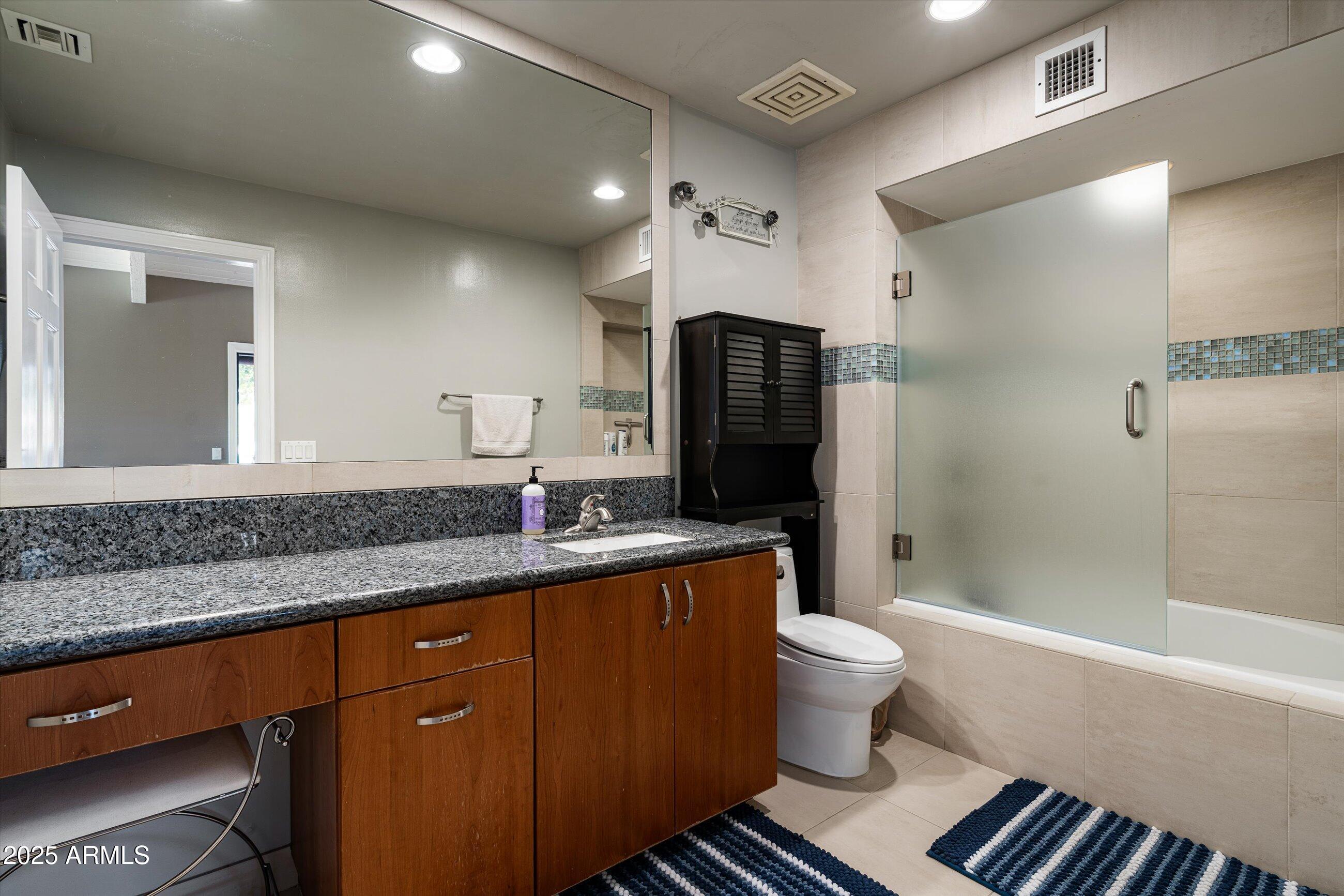 6830 North 46th Place Paradise Valley, AZ 85253 - Photo 29 of 65 a bathroom with a granite countertop sink a toilet a mirror and shower