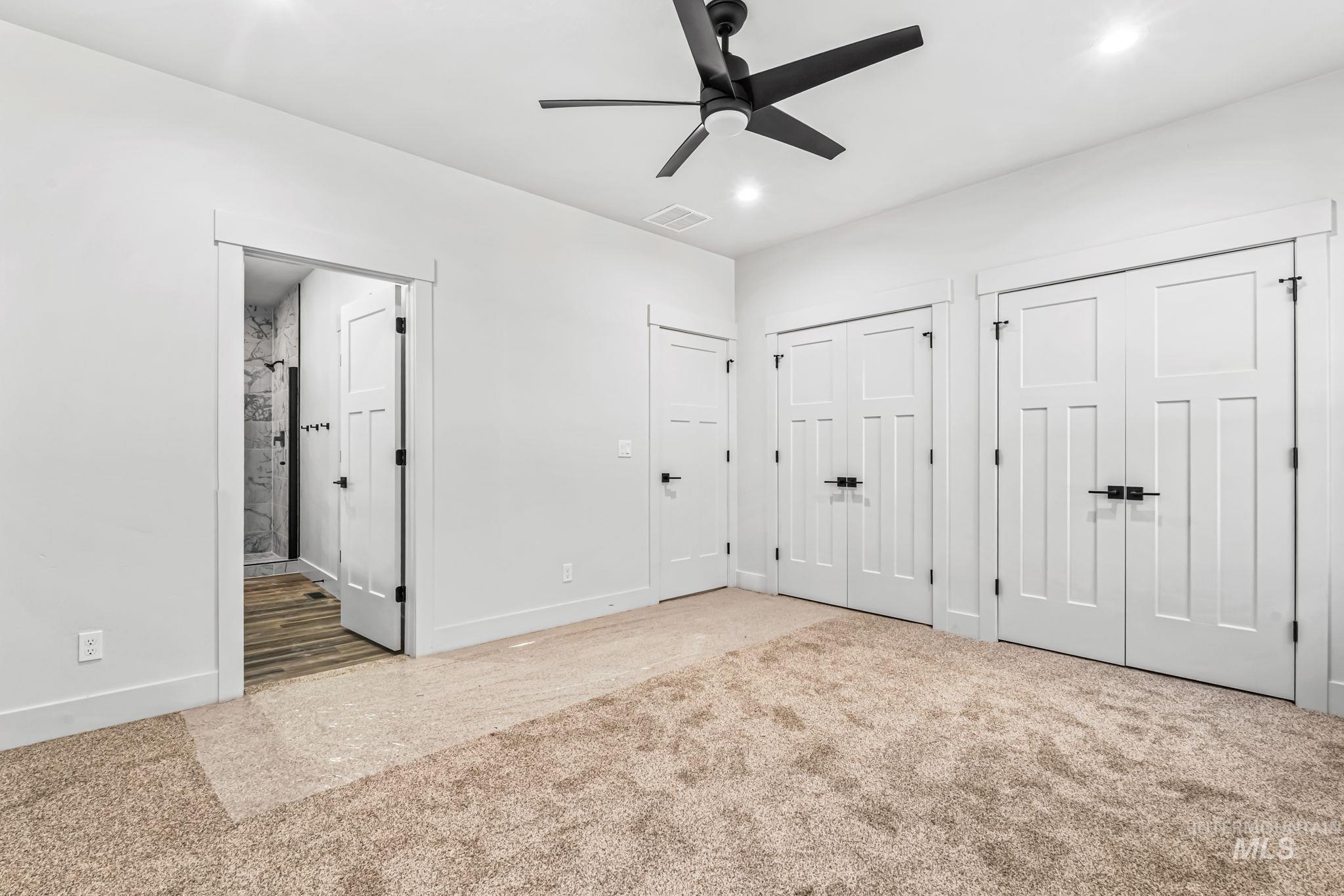 2905 Cypress Point Payette, ID 83661 - Photo 9 of 26 Unfurnished bedroom featuring multiple closets, ensuite bath, carpet flooring, a ceiling fan, and recessed lighting