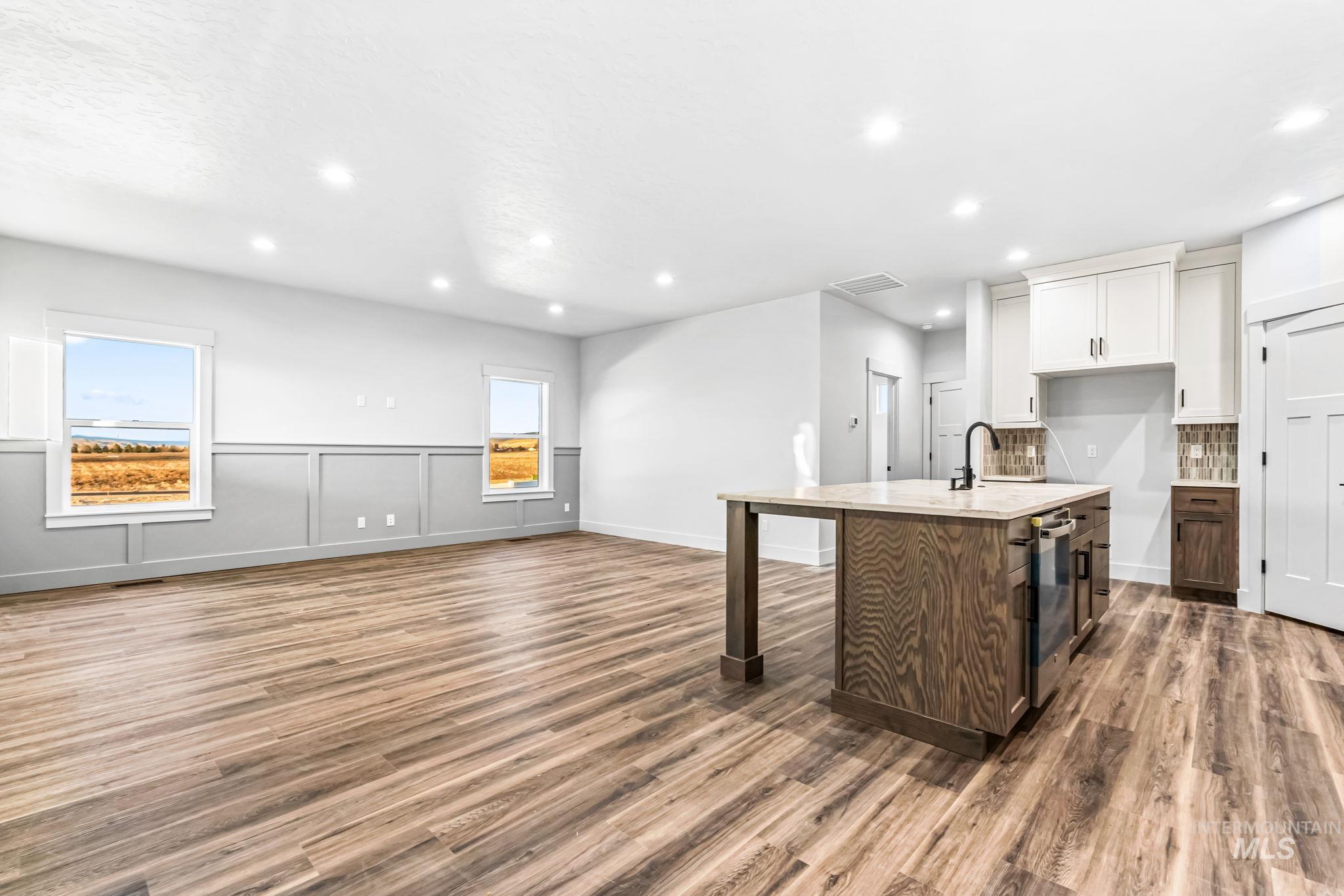 2905 Cypress Point Payette, ID 83661 - Photo 26 of 26 Kitchen featuring white cabinetry, a kitchen island with sink, dark wood finished floors, open floor plan, and a decorative wall